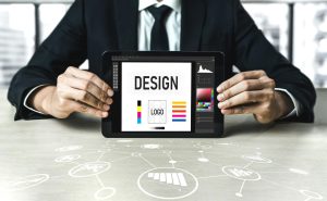 Graphic designer showing a custom logo design draft and brand identity guidelines on a digital tablet screen.