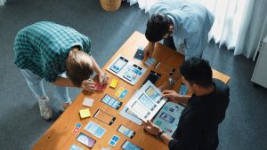 App development team collaborating on mobile UI design wireframes and user flow sketches during a strategy session.