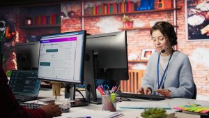 E-commerce support specialist using a headset and computer to manage order tracking and post-launch store maintenance.